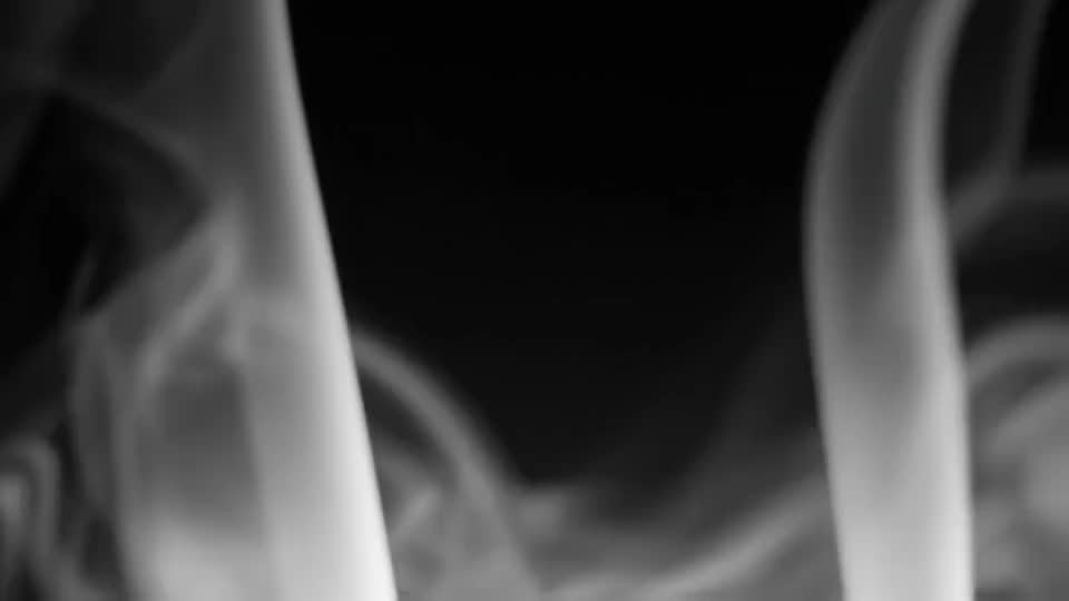 Smoke folds through one hard beam in a black room